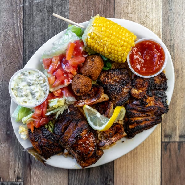 River Smith's seafood platter with blackened fish, shrimp, hushpuppies, corn, salad, and sauces.