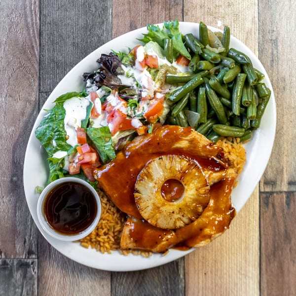 Grilled chicken with pineapple, rice, green beans, and a side salad with dressing and dipping sauce.